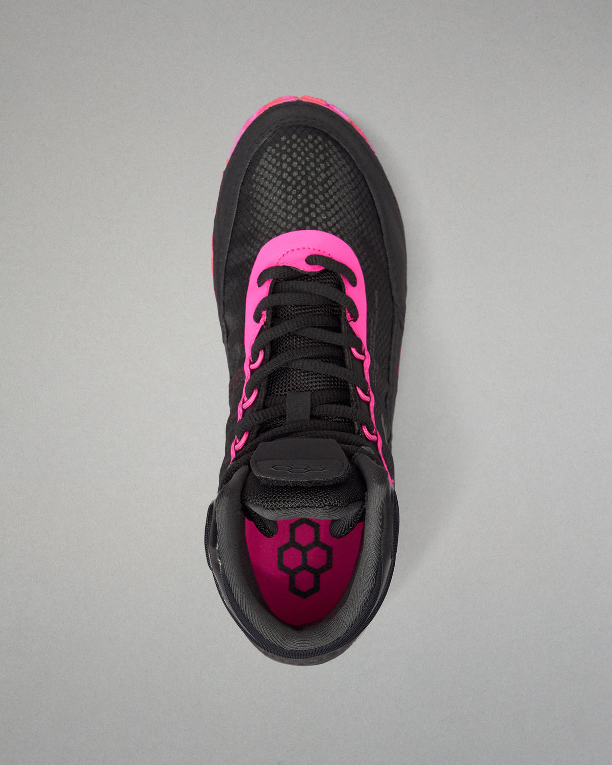 A black athletic wrestling shoe shown from a top-down view, featuring vibrant hot pink accents on the collar, around the laces, and on the inner lining, with a black geometric logo on the tongue.