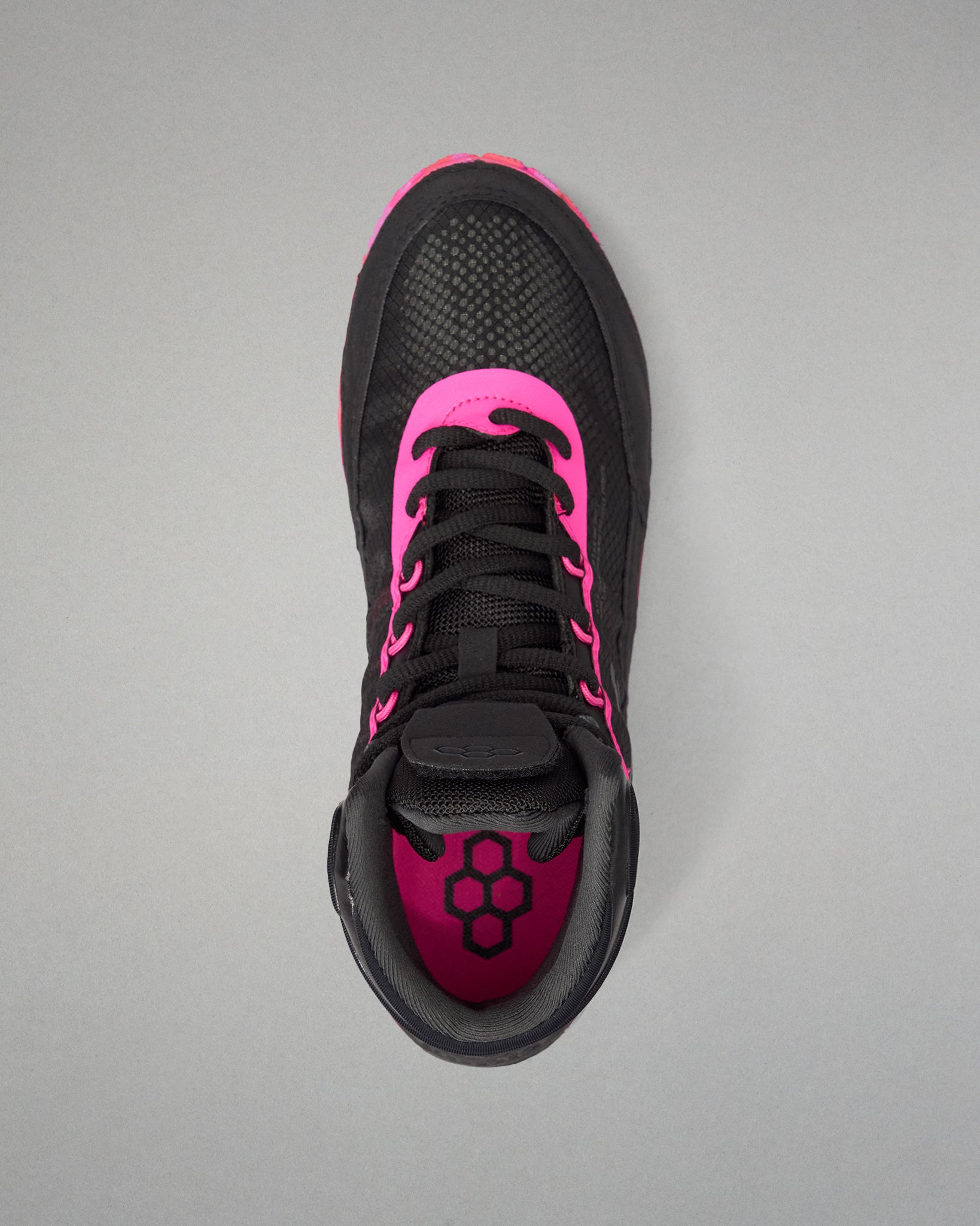 A black athletic wrestling shoe shown from a top-down view, featuring vibrant hot pink accents on the collar, around the laces, and on the inner lining, with a black geometric logo on the tongue.