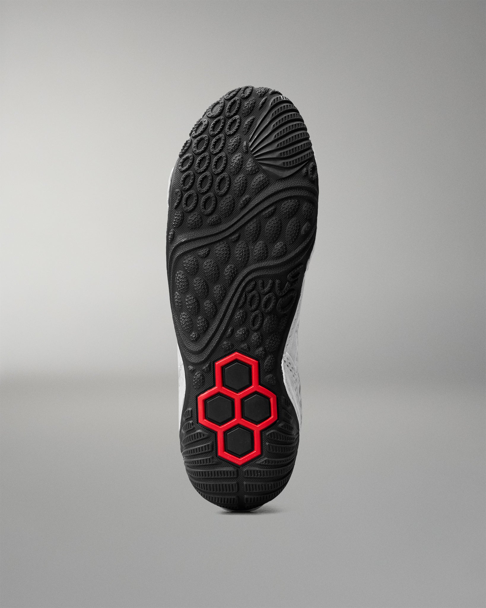 Bottom outsole view of RUDIS Infinity Edge wrestling shoe featuring aggressive traction pattern and red hex grip technology