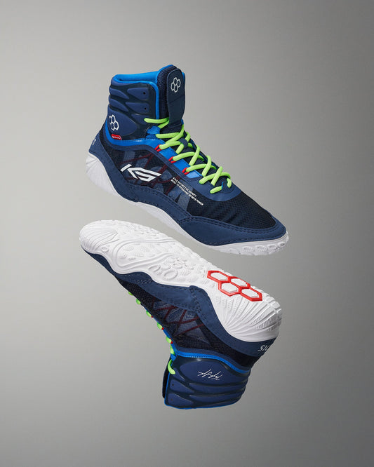 Wrestling shoes with blue, white, and green design on a gray background