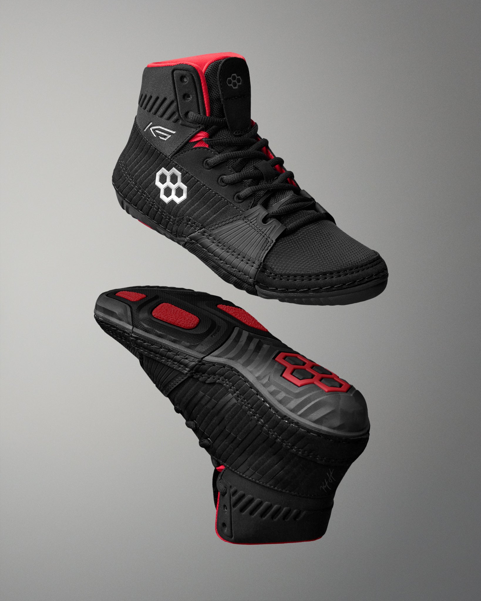 Black wrestling shoes with red accents on a gray background