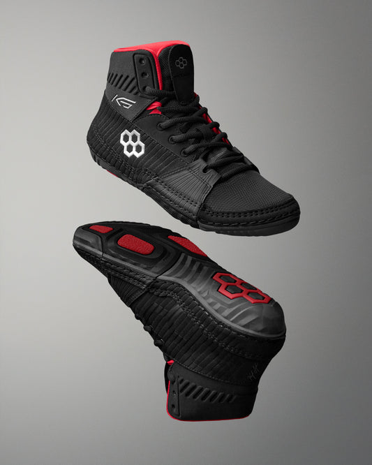 Black wrestling shoes with red accents on a gray background