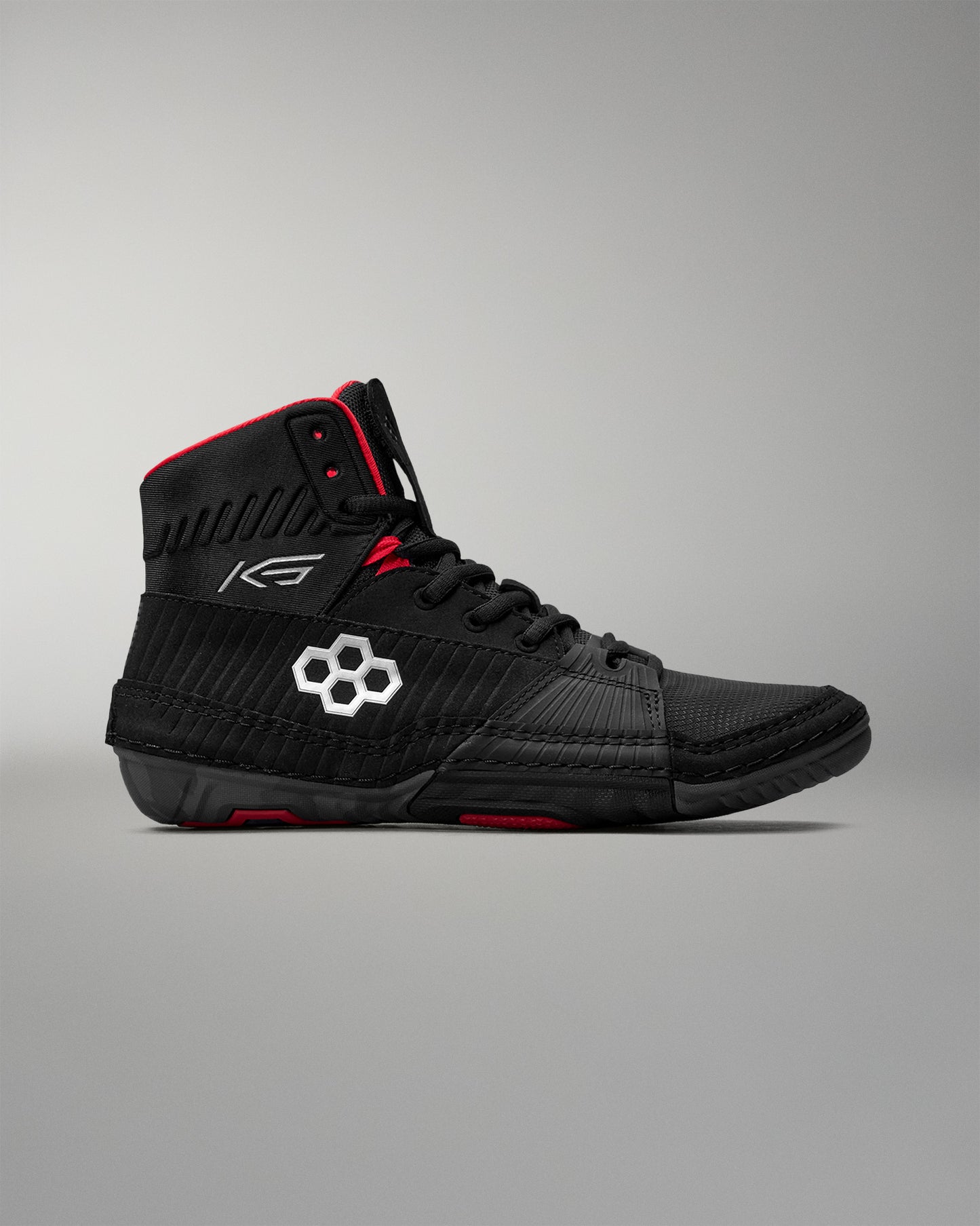 Black wrestling shoe with red accents on a gray background