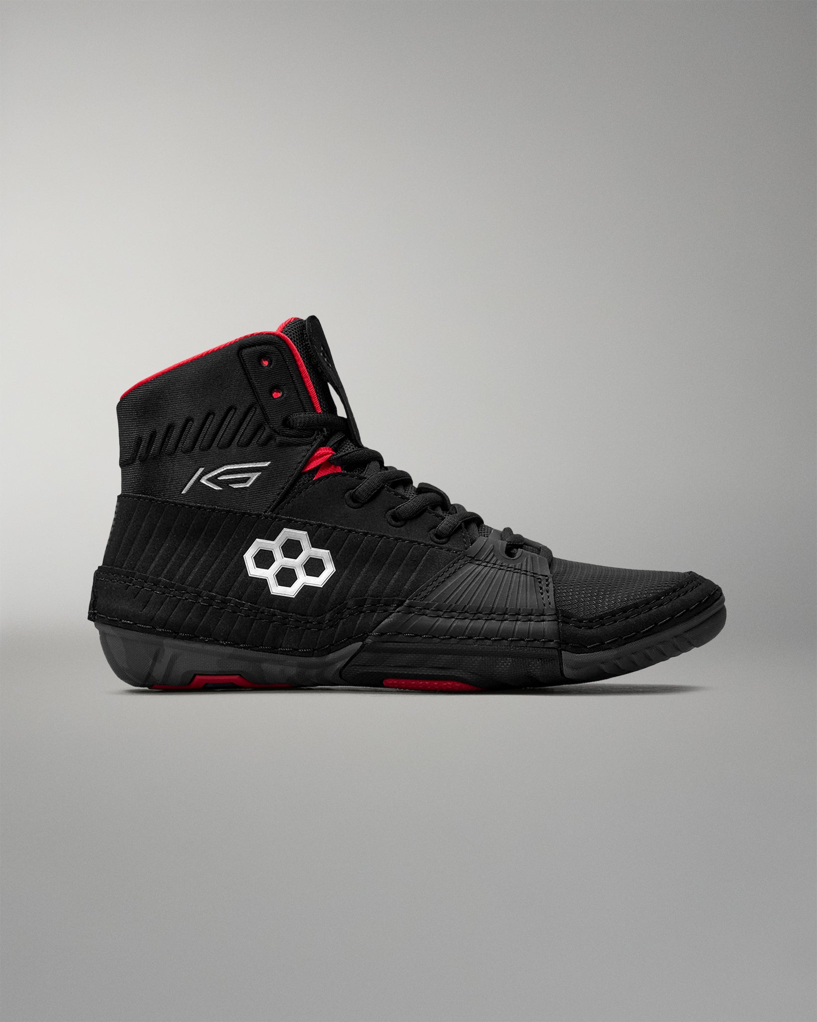 Black wrestling shoe with red accents on a gray background