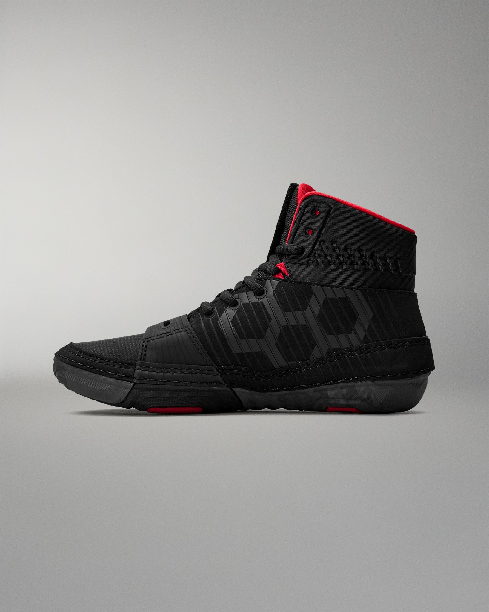 Black wrestling shoe with red accents on a gray background