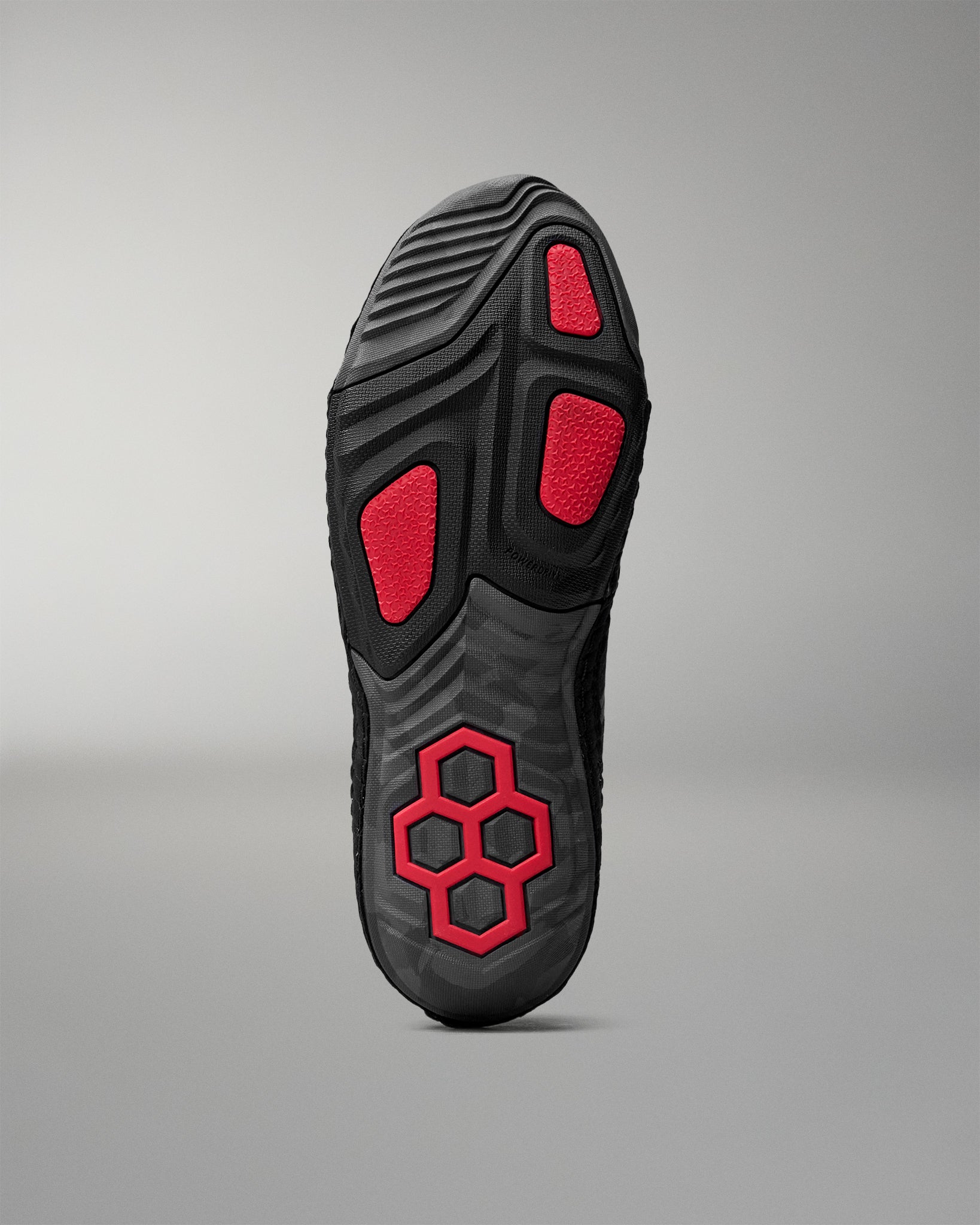 Black wrestling shoe sole with red accents on a gray background