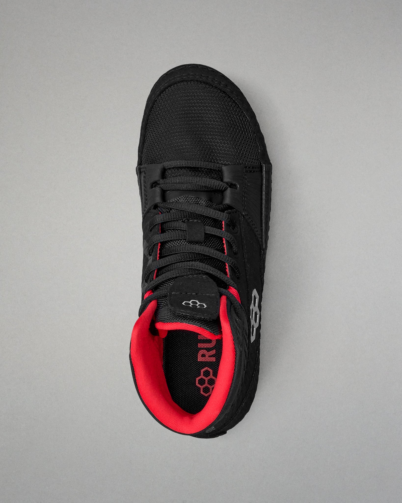 Black wrestling shoe with red interior on a gray background