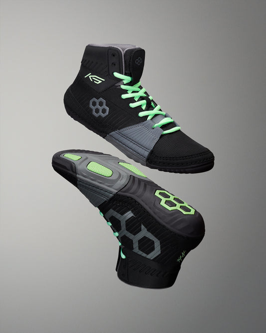 Black and gray wrestling shoes with green accents on a gray background