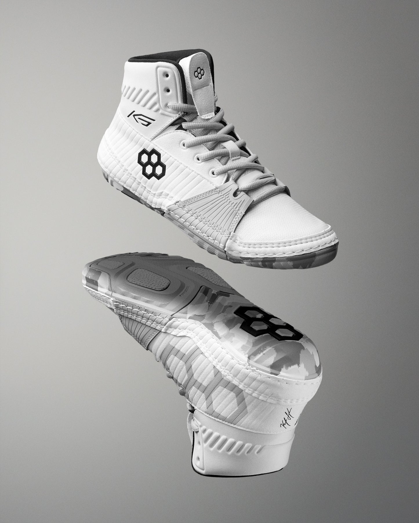 White wrestling shoes with black logo on a gray background