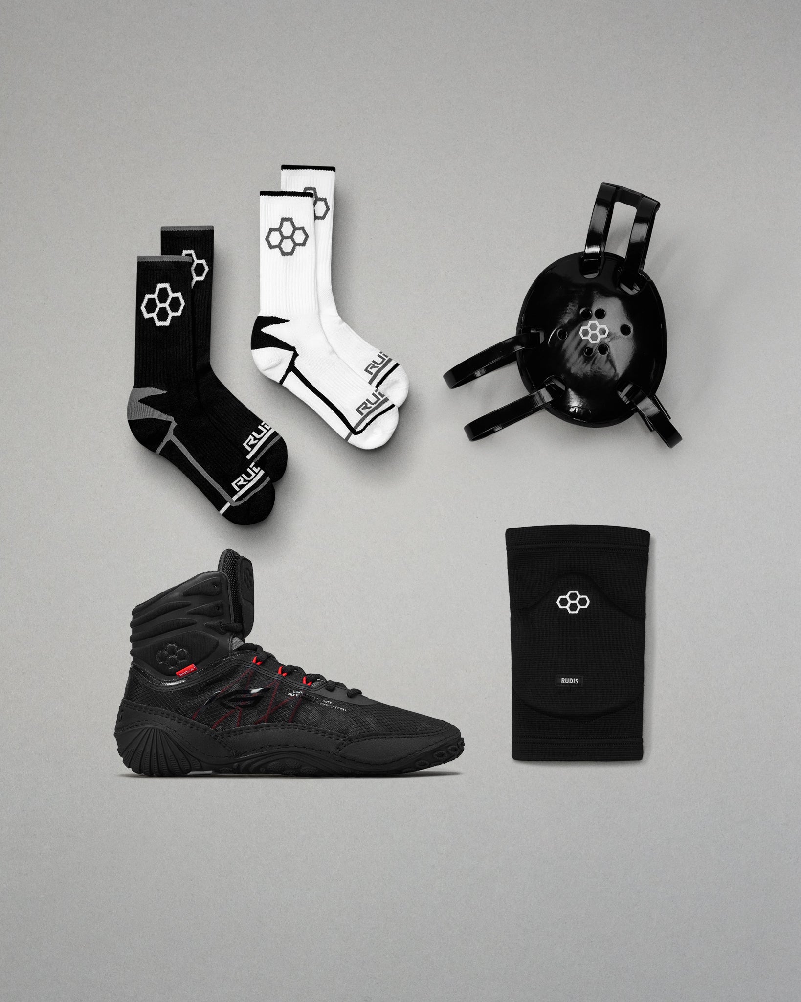 Collection of black and white wrestling shoes, socks, and accessories on a gray background