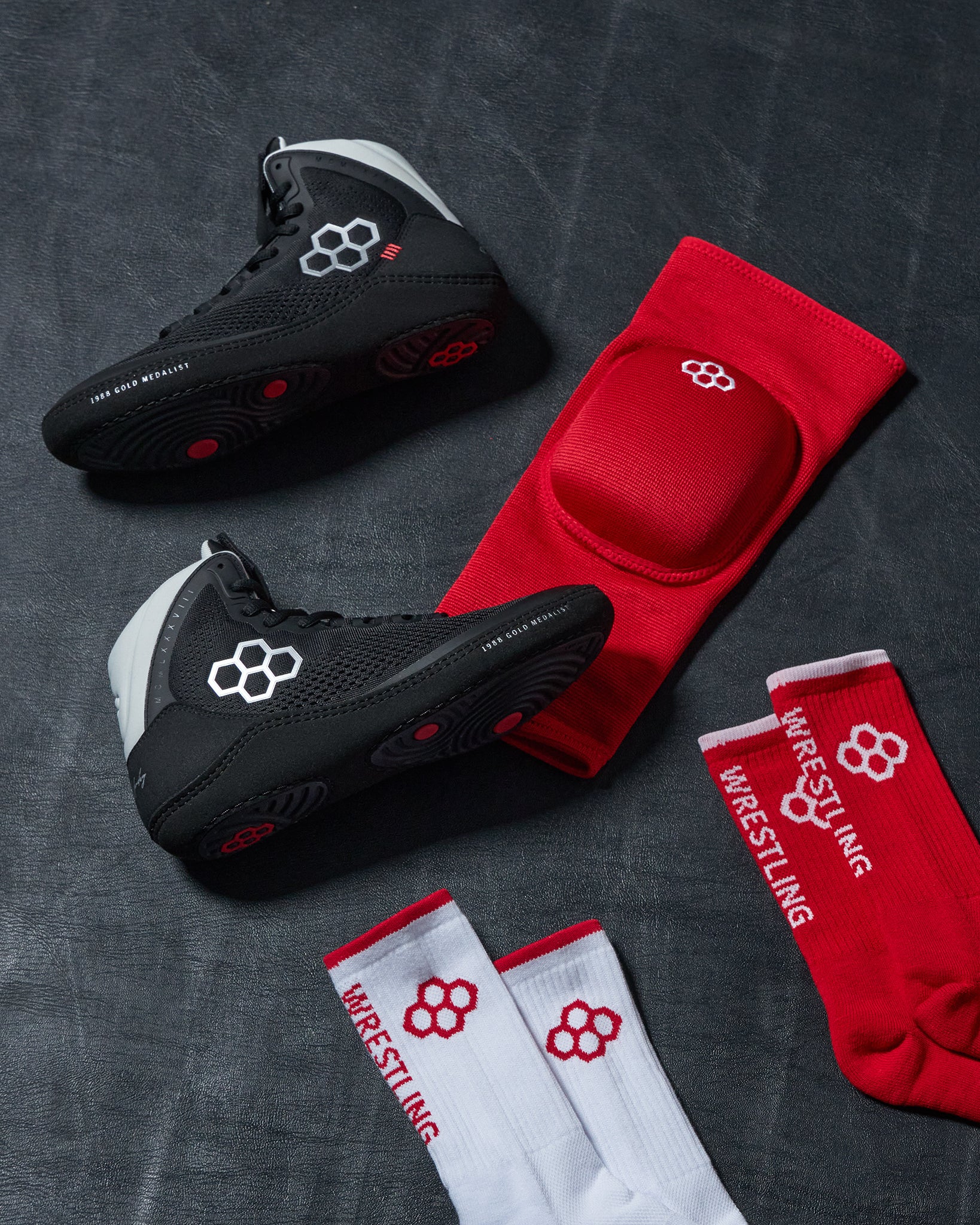 Black wrestling shoes and red and white socks on a dark textured background
