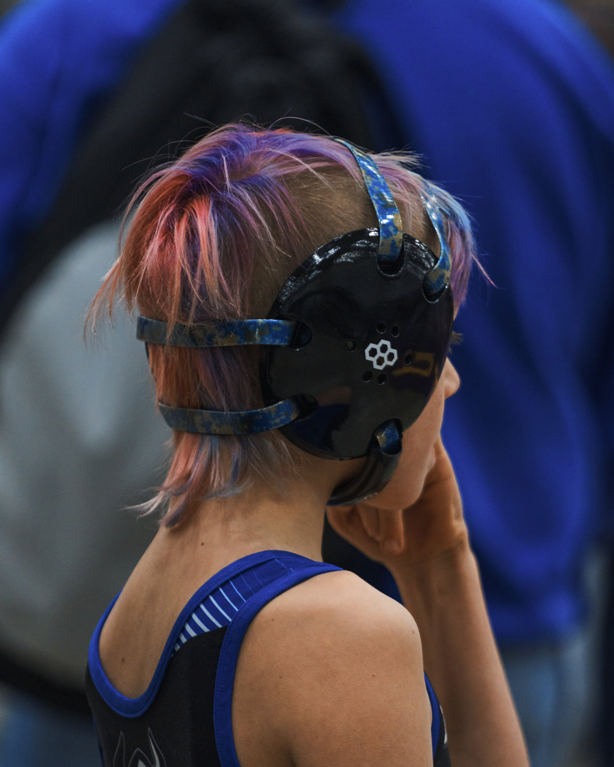 Youth wrestler with colorful red and blue hair wearing RUDIS black headgear and a blue singlet during the Kids Folkstyle National Championship. 