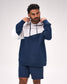 A man wearing a navy blue and white color-blocked Lacrosse hoodie with matching navy shorts, posing against a light gray studio background.