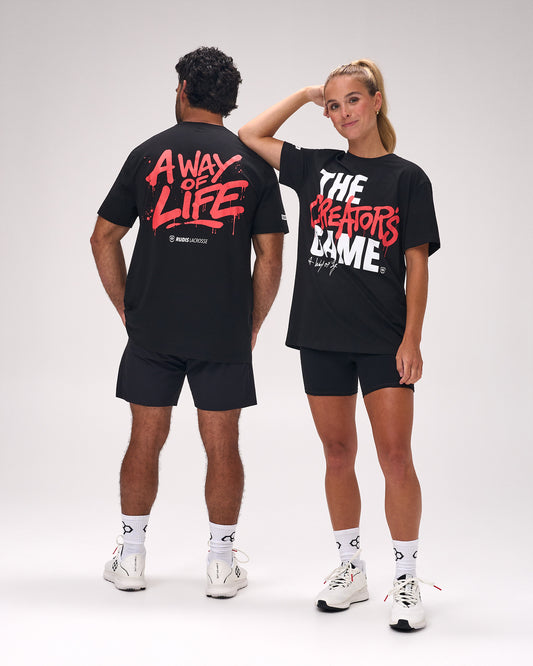 Male and female athletes wearing the RUDIS The Creator's Game Hybrid T-Shirt in Black featuring bold front "The Creator's Game" graphic and oversized "A Way of Life" artwork on the back.