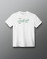 A white short-sleeve crewneck t-shirt with a green signature-style graphic and small text printed on the center chest, displayed against a dark gray gradient background.