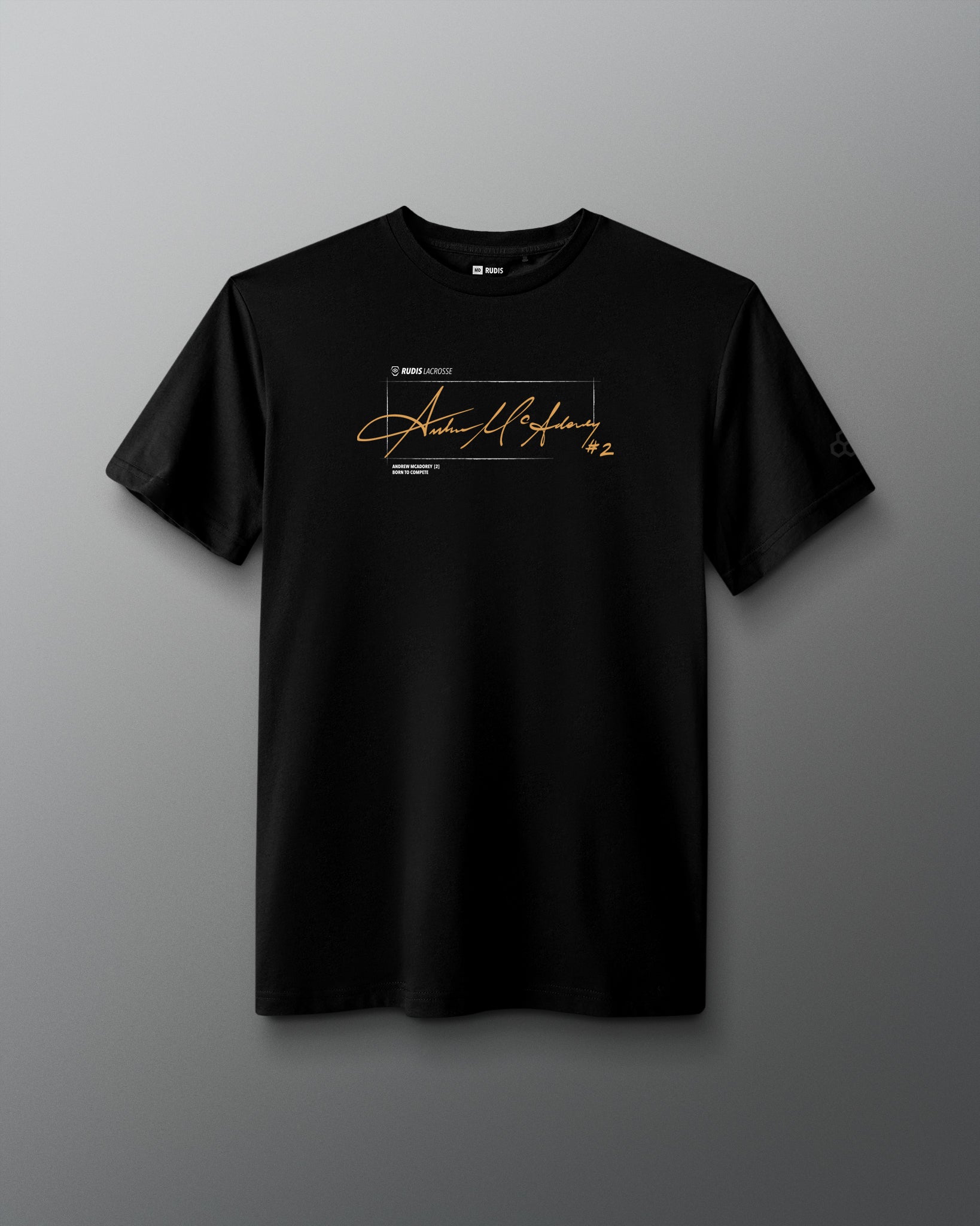 A black short-sleeve crewneck t-shirt featuring a gold cursive signature graphic and small white text on the chest, displayed against a dark gray gradient background.