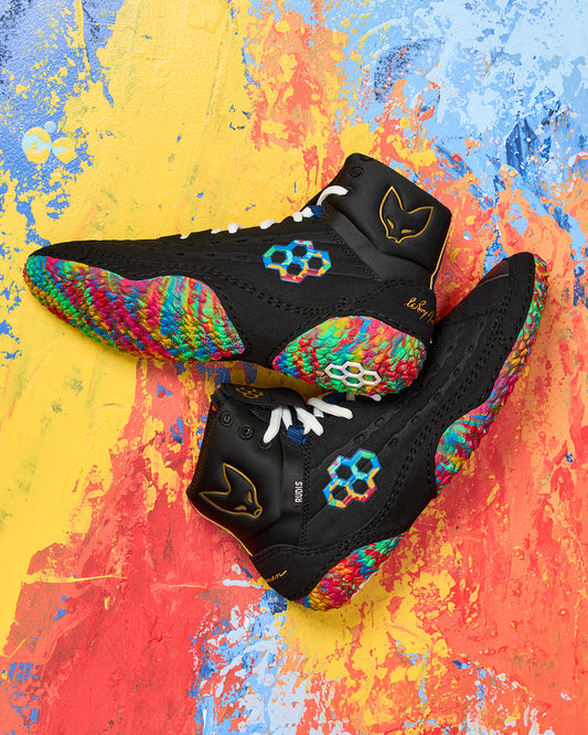 Black wrestling shoes with colorful pattern on a multicolored abstract background