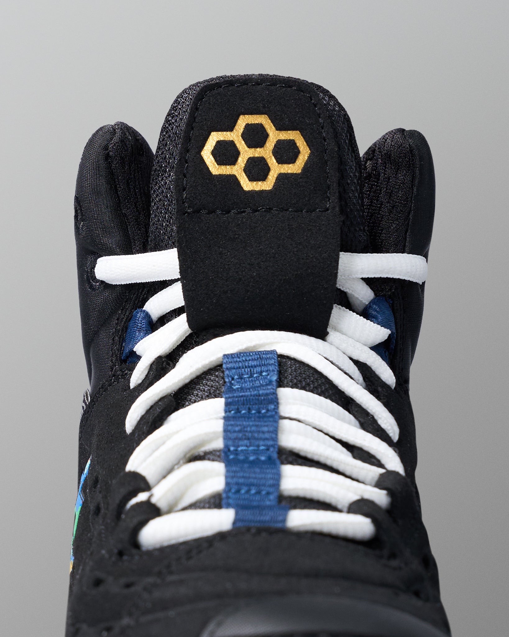 Black wrestling shoe with white laces and blue accents on a gray background