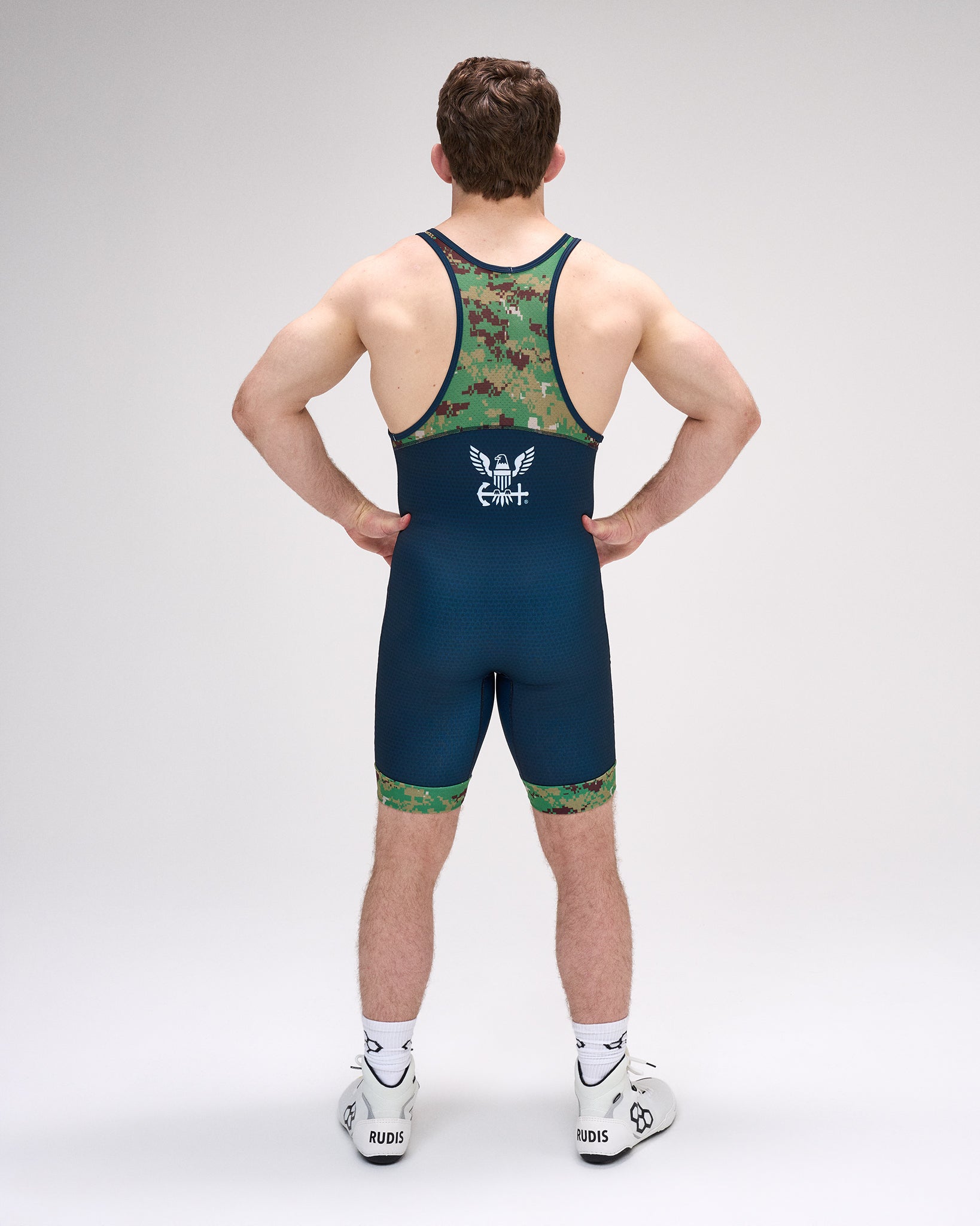 Person wearing a blue and green wrestling singlet on a gray background