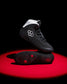 Black wrestling shoes with white accents on a red and black background