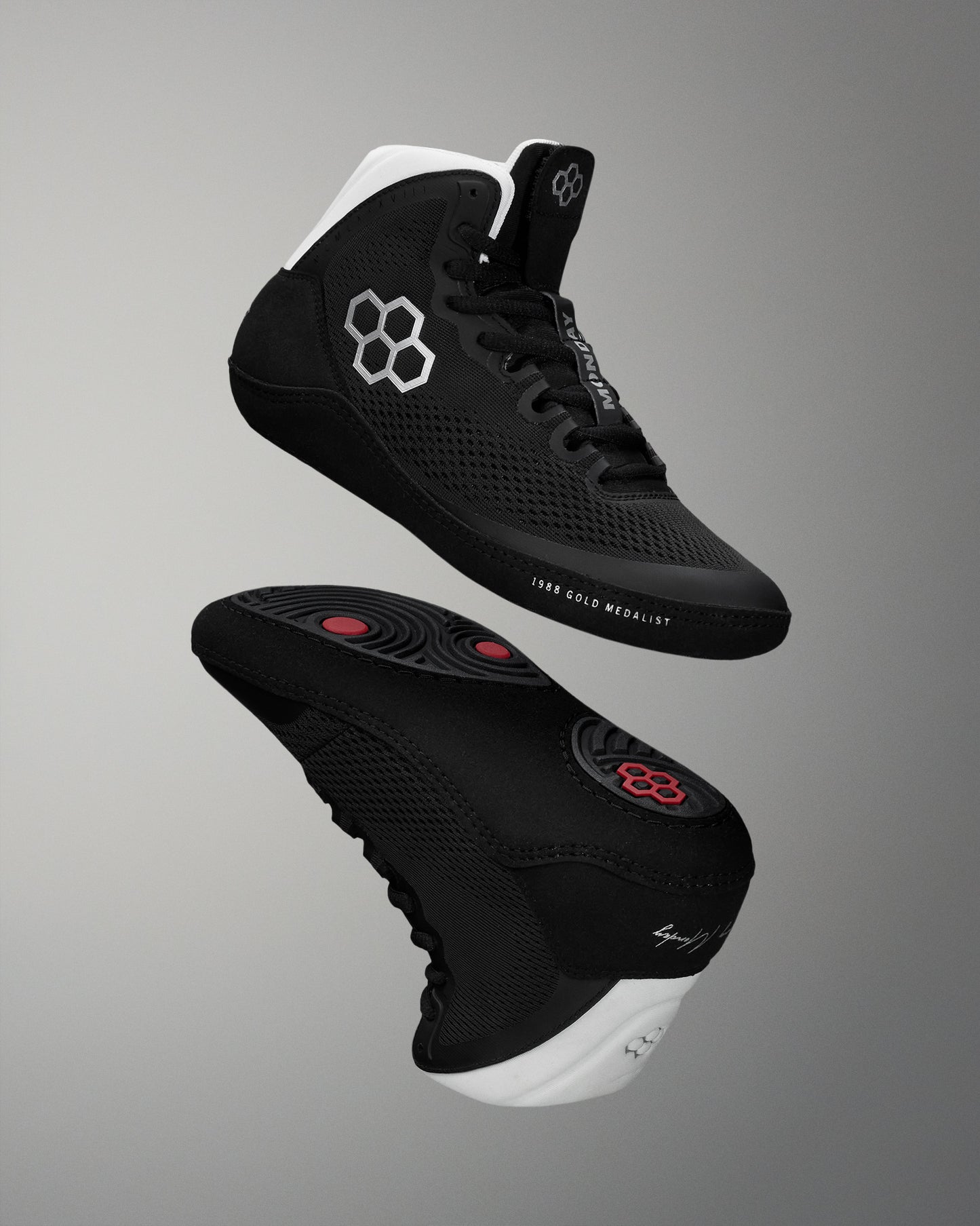 Black wrestling shoes with white soles on a gray background