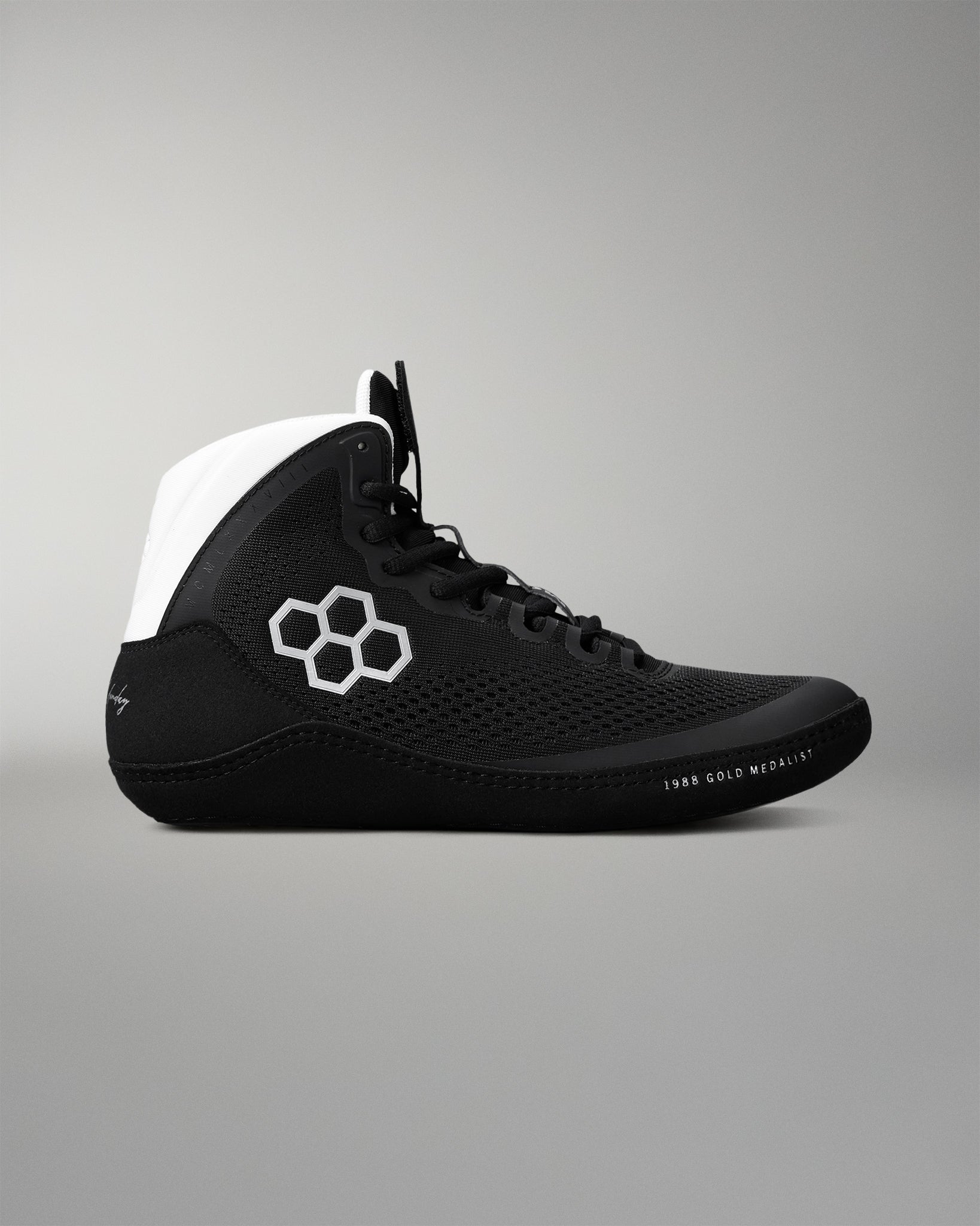 Black wrestling shoe with white accents on a gray background