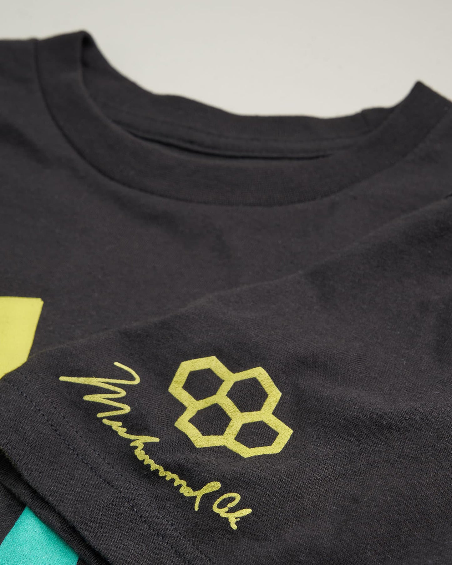 A close-up view of a black t-shirt featuring vibrant geometric designs and a signature