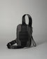 A compact black crossbody bag showcases a textured back for enhanced grip, featuring an adjustable strap for comfort and durability against a light gray background.