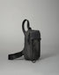 Compact black crossbody bag with a durable strap and secure zippers, designed for casual use or travel, set against a soft gray background.