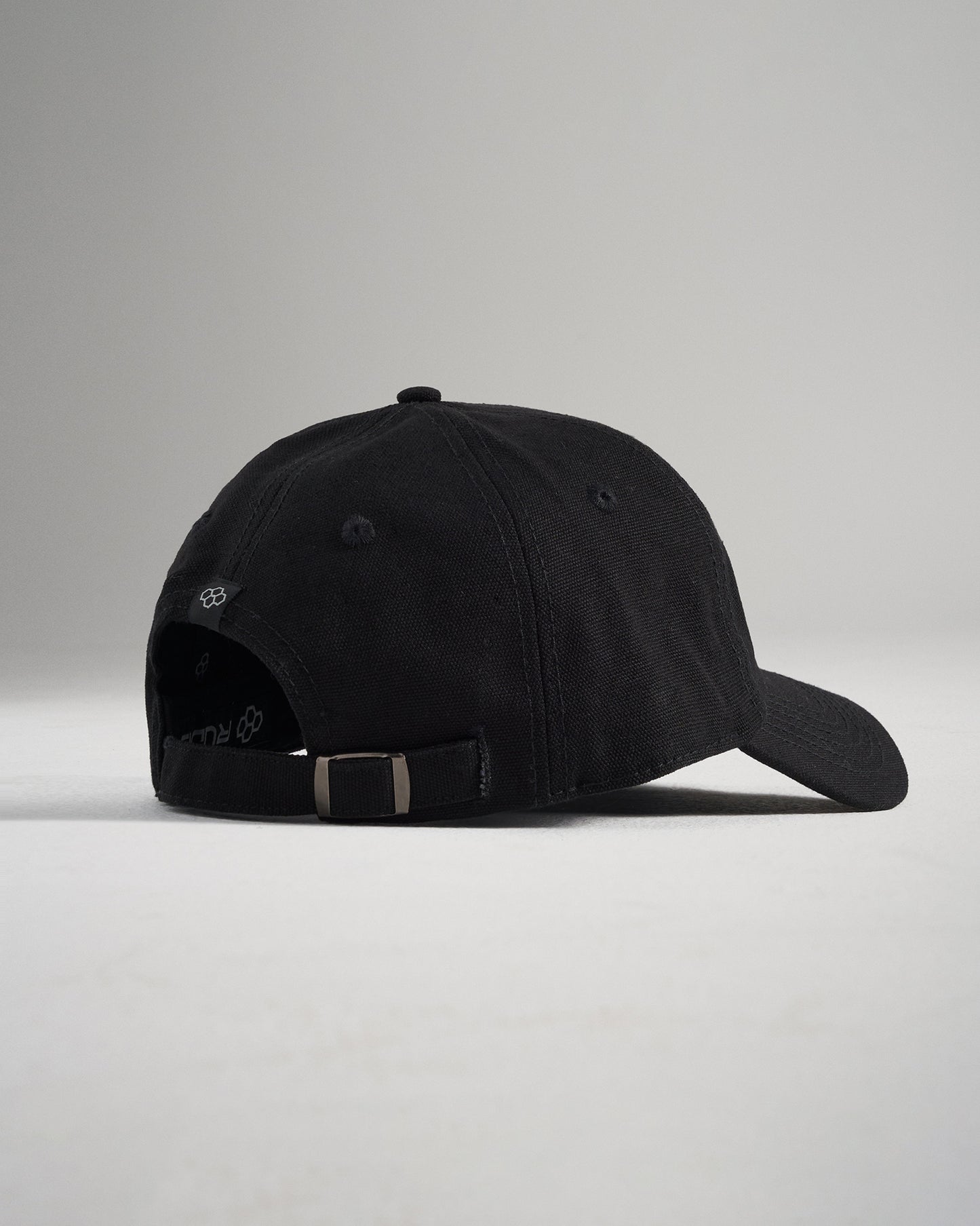 A black baseball cap viewed from the back featuring a classic adjustable strap with a metal buckle