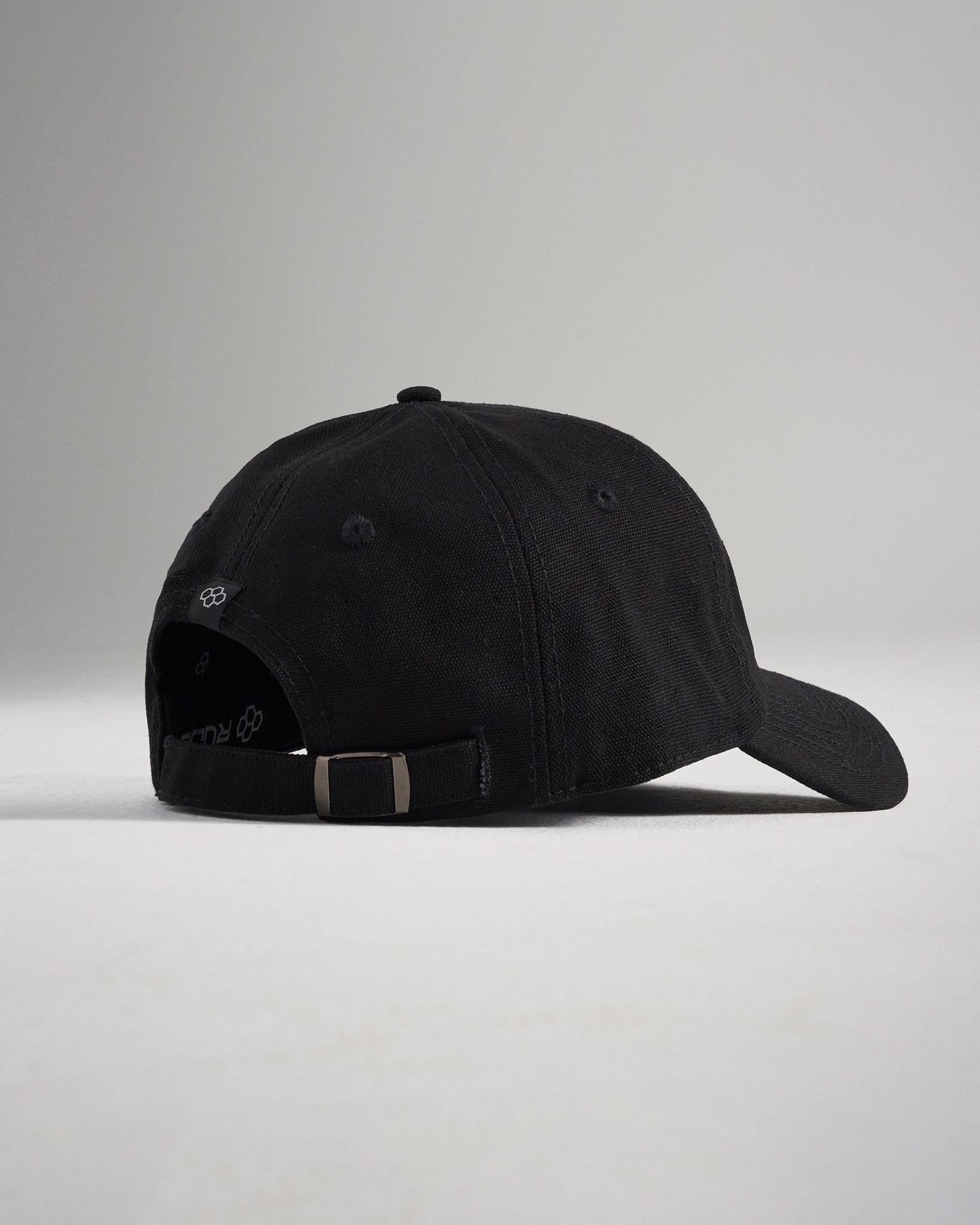 A black baseball cap viewed from the back featuring a classic adjustable strap with a metal buckle