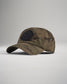 A stylish camo baseball cap featuring a round black patch with a brand name emblem designed for both casual wear and outdoor activities