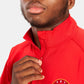 A young man in a bright red jacket adjusting the collar with a focused expression on his face