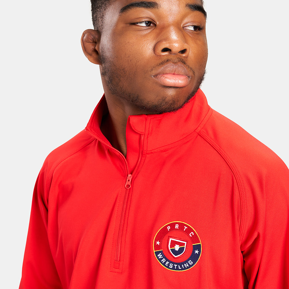 A young man showcasing a vibrant red athletic half-zip shirt with a wrestling emblem exuding confidence and focus