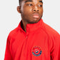 A young man showcasing a vibrant red athletic half-zip shirt with a wrestling emblem exuding confidence and focus
