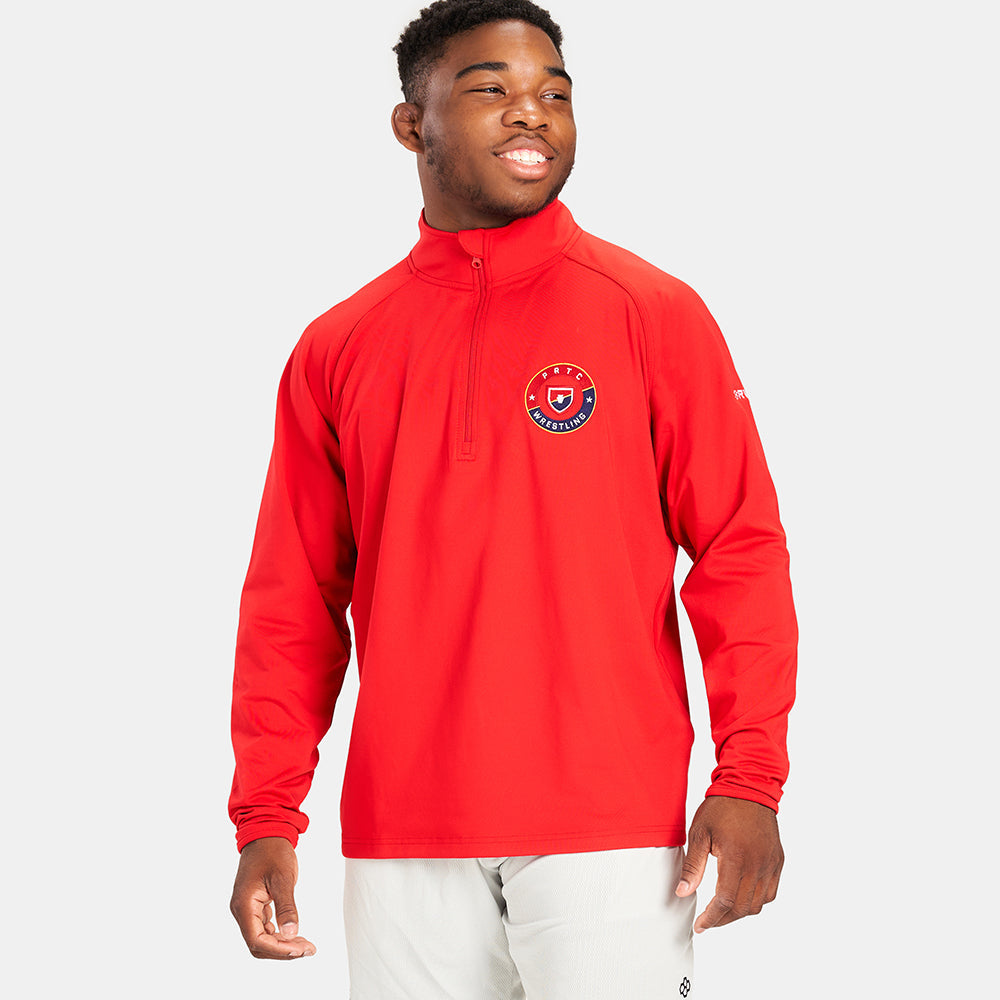 A young man wearing a vibrant red long-sleeve athletic shirt featuring a wrestling logo on the chest and smiling confidently against a plain light gray background
