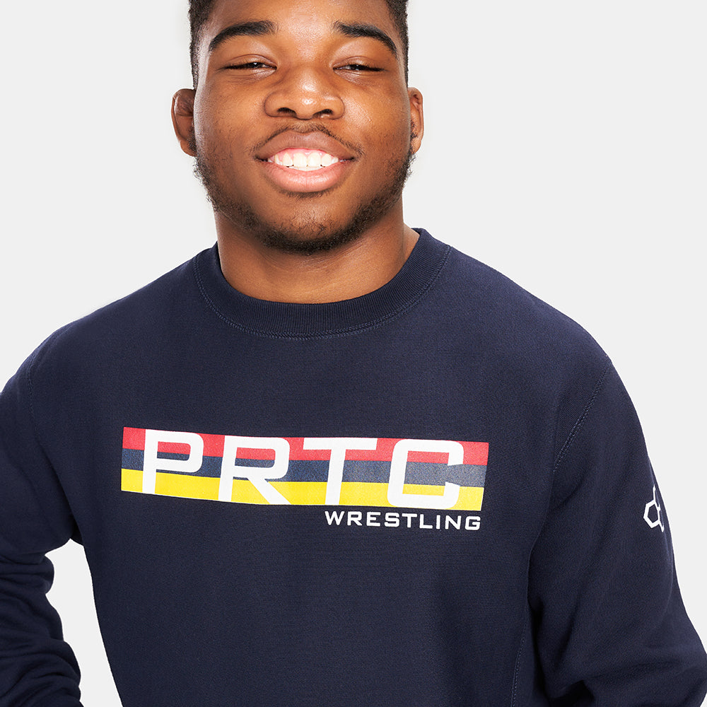 A smiling young man wears a navy blue sweatshirt emblazoned with PRTC WRESTLING in bold colors on the front