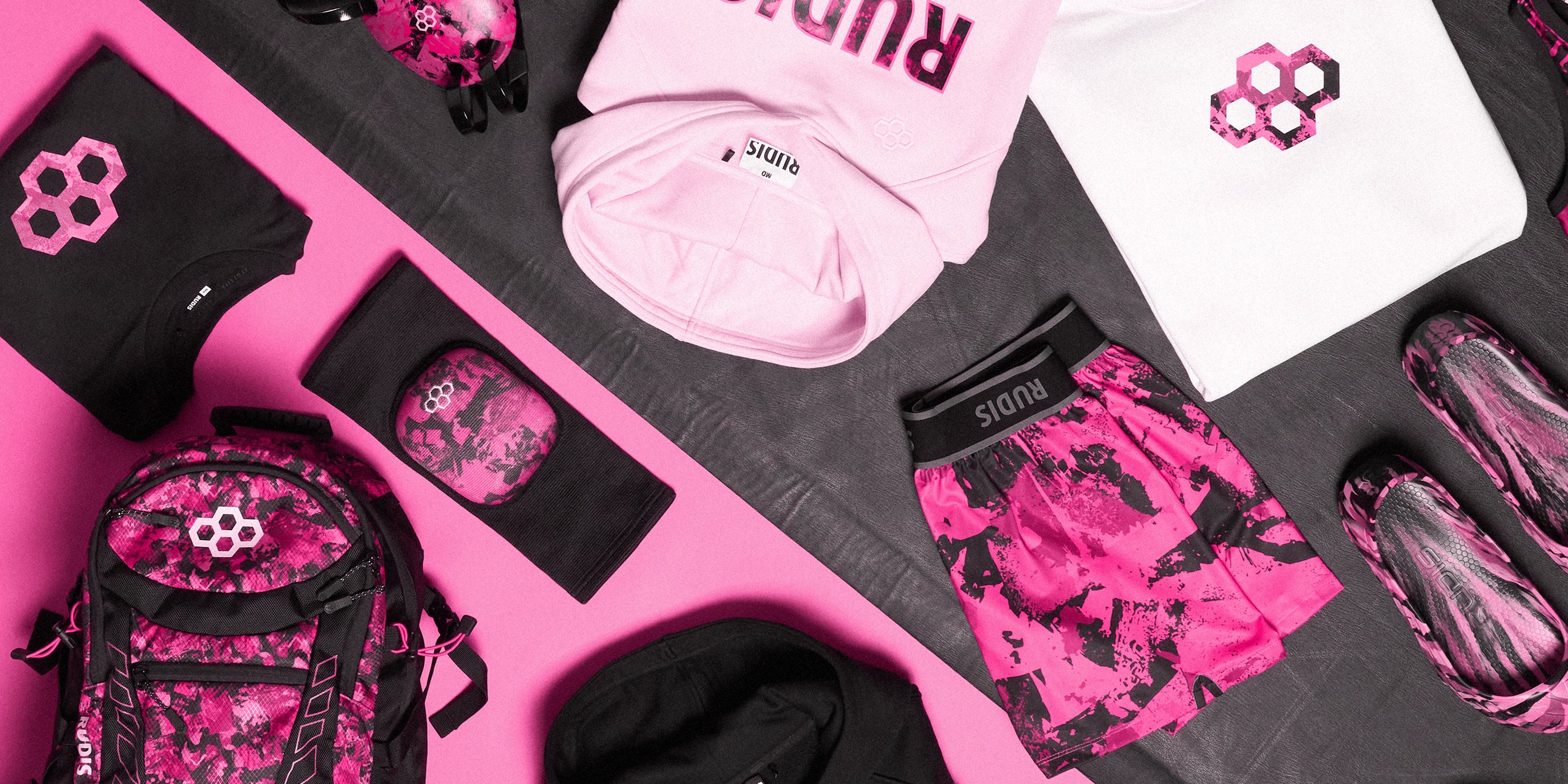 The RUDIS Pink Power Collection featuring bold pink and black wrestling gear including backpacks, wrestling shoes, apparel, headgear, knee pads, and shorts – designed for wrestlers who want style and performance on and off the mat.