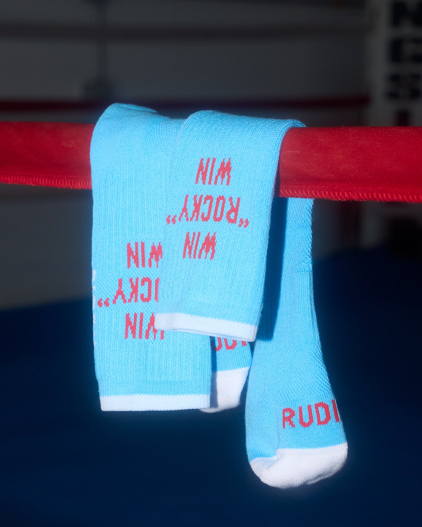 Blue socks with red text hanging on a red bar, likely in a boxing ring.