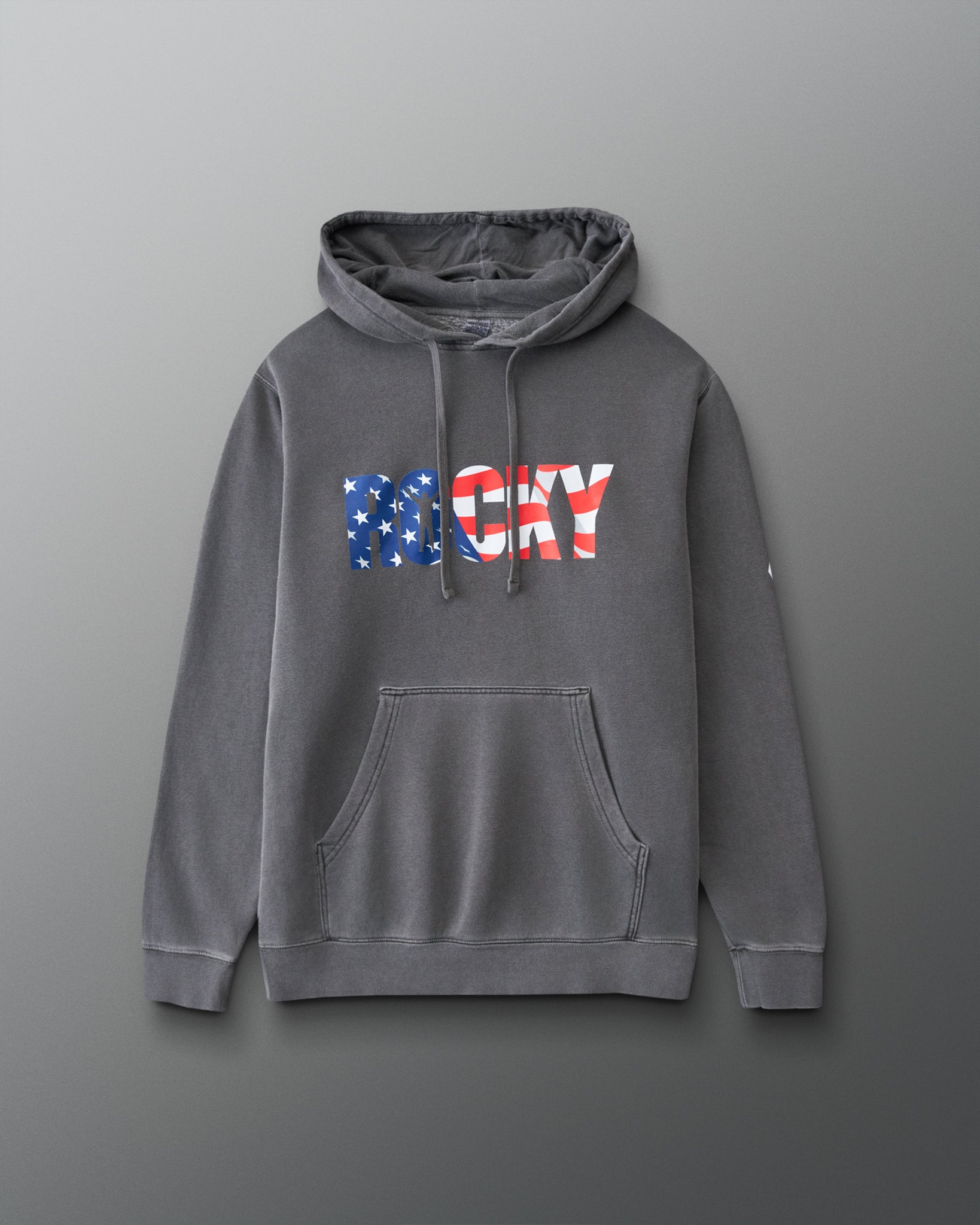 A dark gray pullover hoodie with a front kangaroo pocket and a 'ROCKY' graphic across the chest in an American flag pattern, displayed on a neutral gray background.
