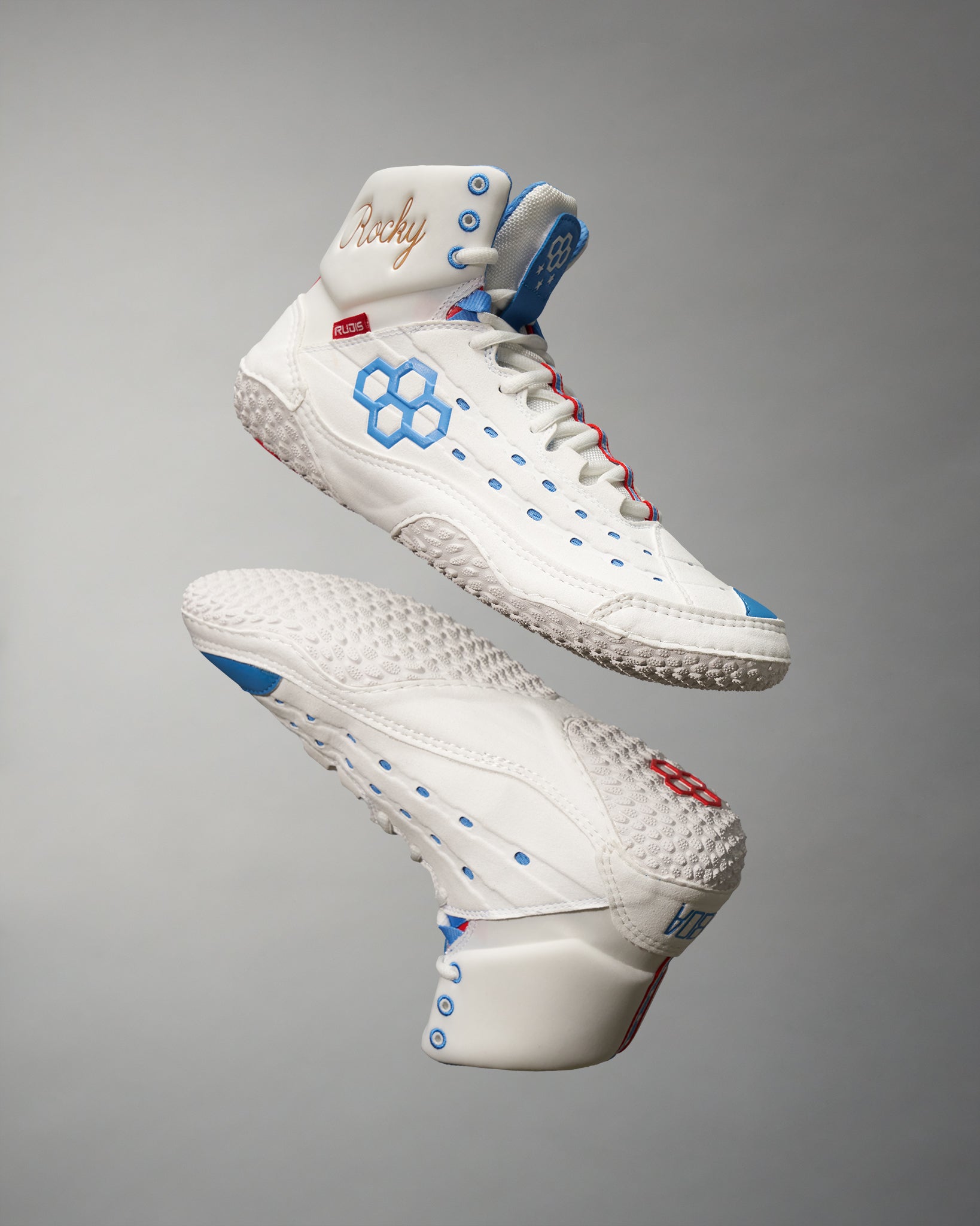 A pair of stylish white high-top shoes with blue and red accents featuring a unique honeycomb pattern and a bold design for athletic performance