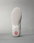 A close-up of the sole of a white athletic shoe featuring a unique textured pattern for grip and a striking red logo