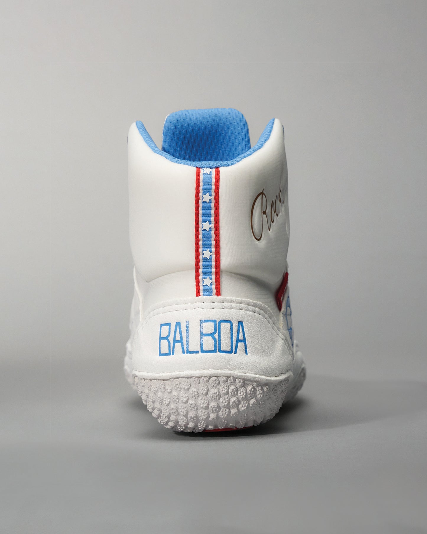 A rear view of a modern white sneaker designed for athletic use featuring blue and red accents along the heel and a textured sole for grip