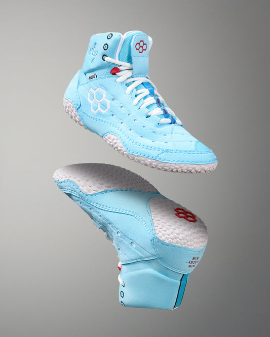 Light blue wrestling shoes with white laces on a gray background
