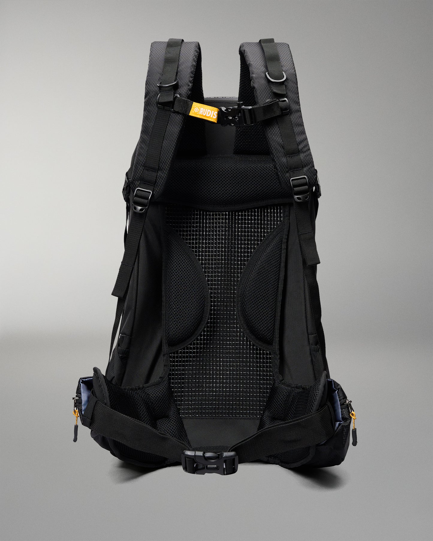 The back view of a black hiking backpack, showing the breathable mesh back panel, padded shoulder straps, and side compression buckles against a neutral gray background.