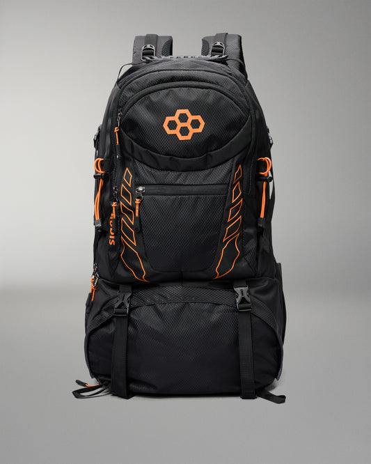 A black technical backpack with bright orange accents, including a geometric logo on the front pocket and vertical branding details, shown against a neutral gray background.