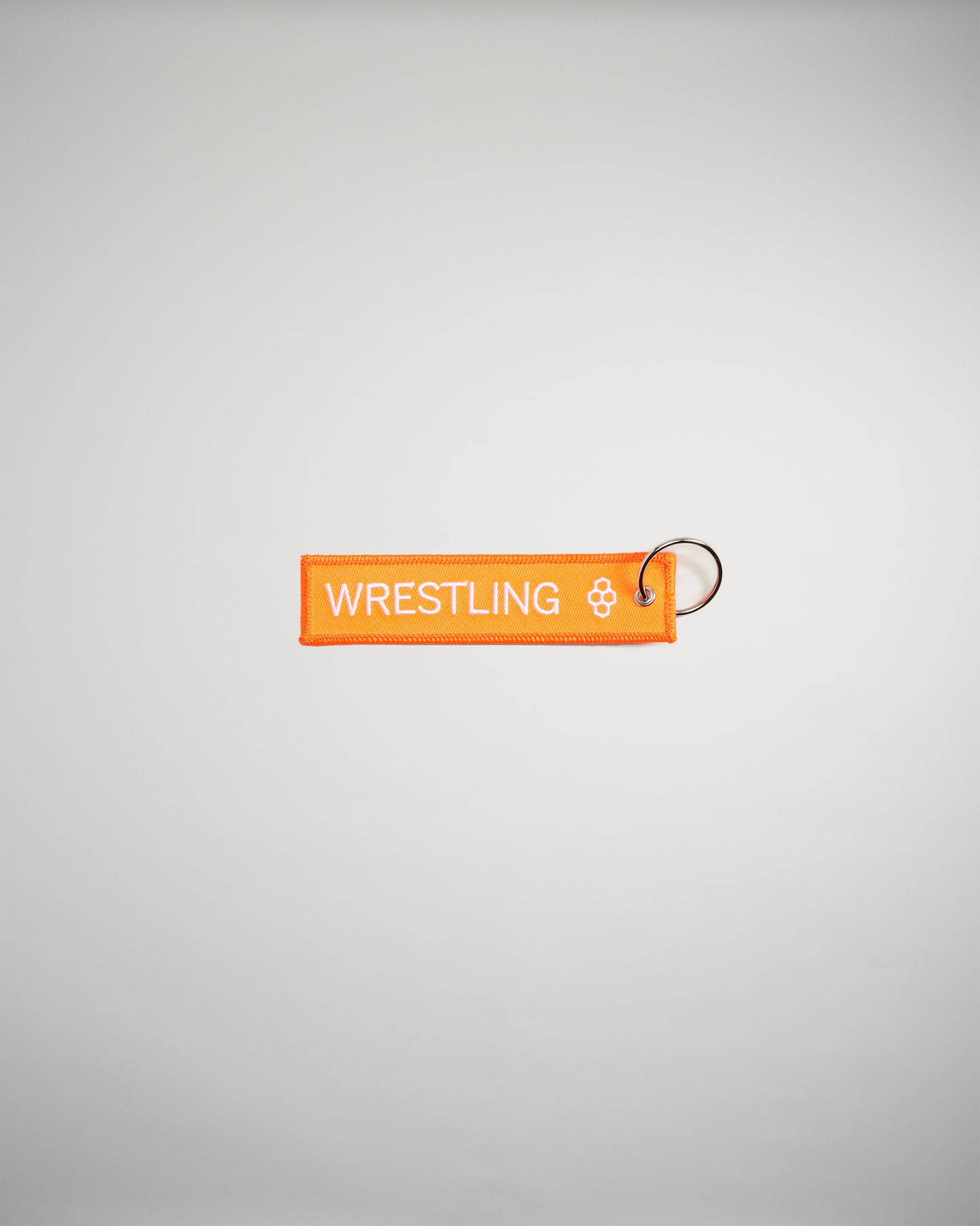 An orange fabric keychain tag featuring the word WRESTLING in bold white letters attached to a metal keyring