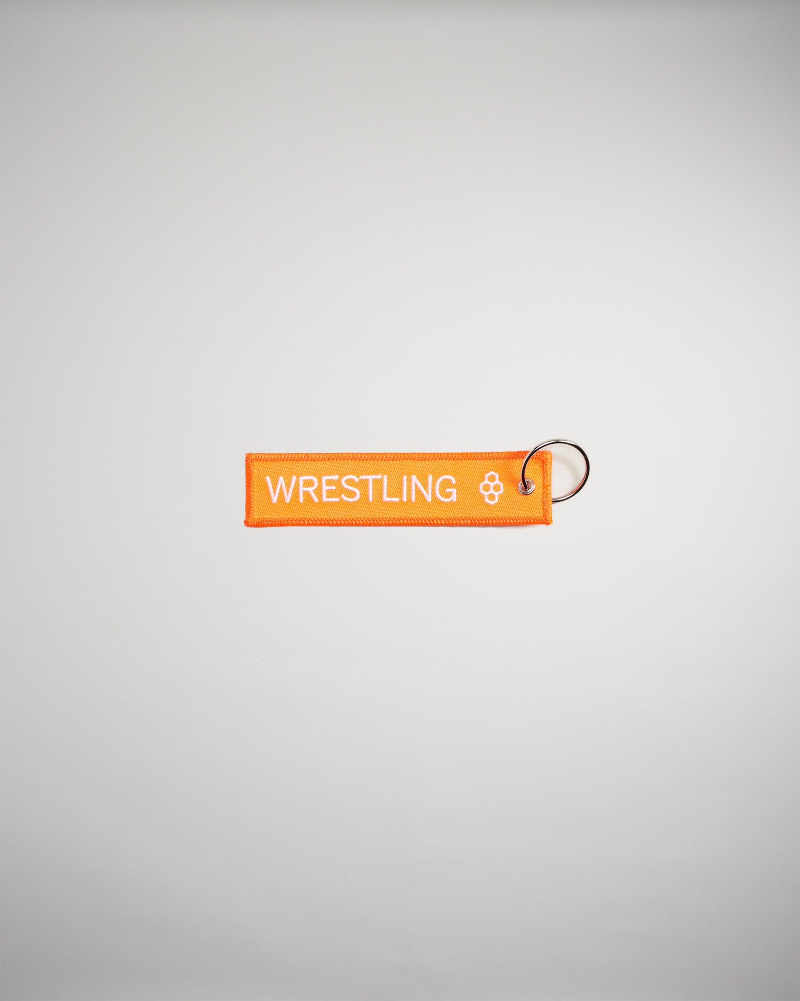 An orange fabric keychain tag featuring the word WRESTLING in bold white letters attached to a metal keyring