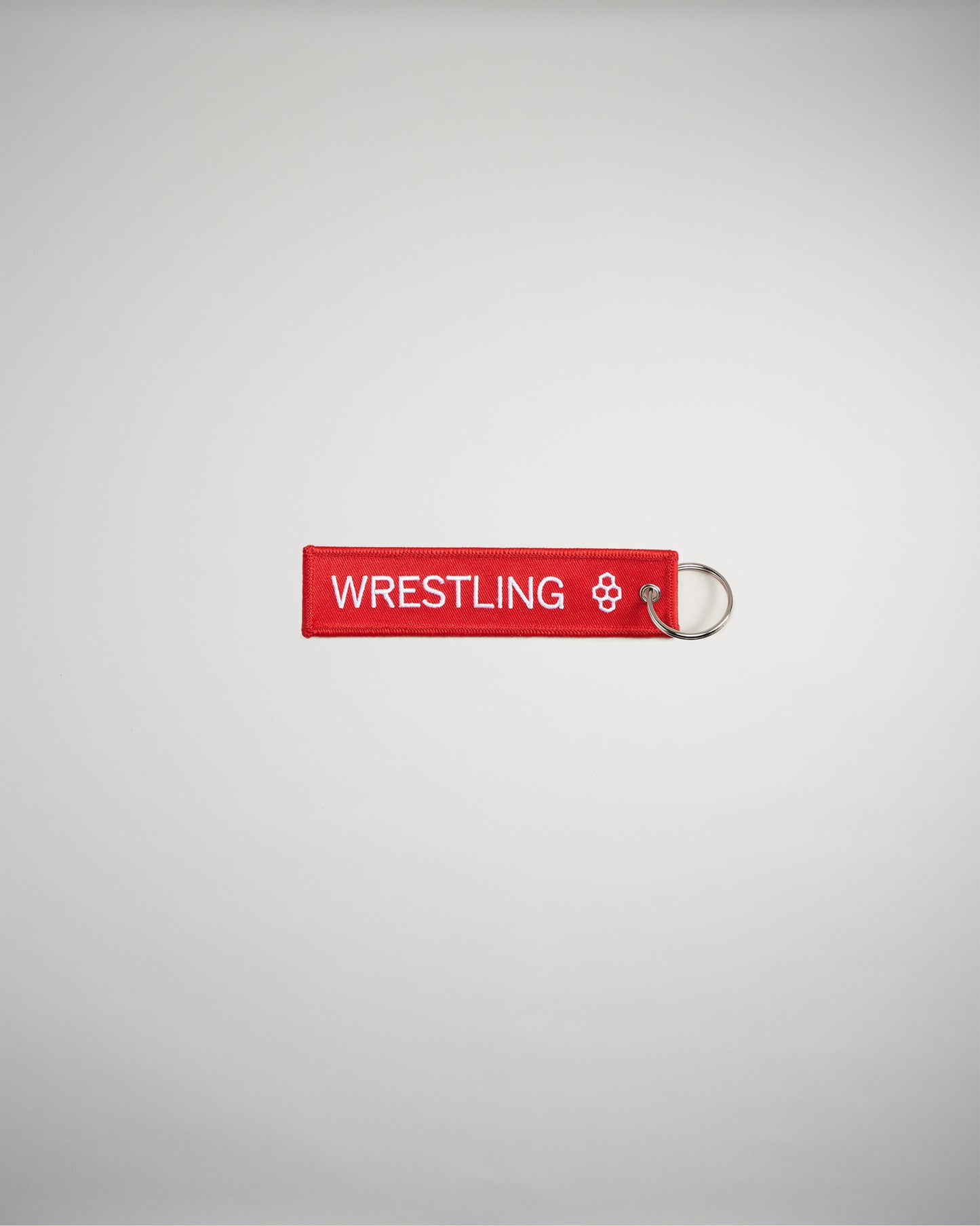 A red keychain tag featuring the word WRESTLING in bold white letters attached to a metal ring against a plain background