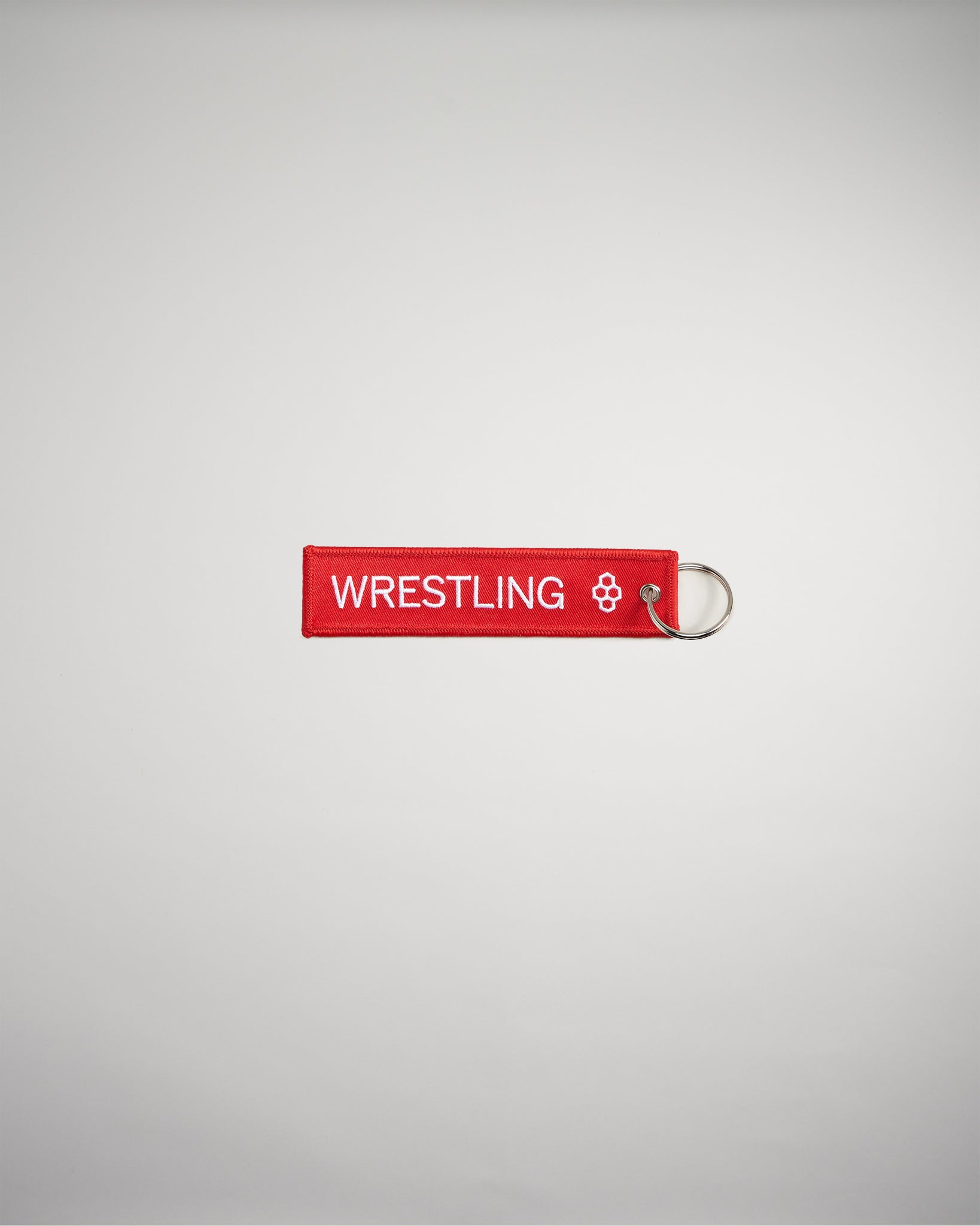 A red keychain tag featuring the word WRESTLING in bold white letters attached to a metal ring against a plain background